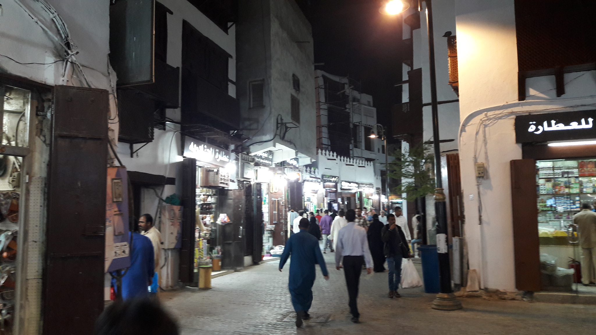 People walking through an illuminated street in Al-Balad / أشخاص يمشون في شارع مضاء في البلد